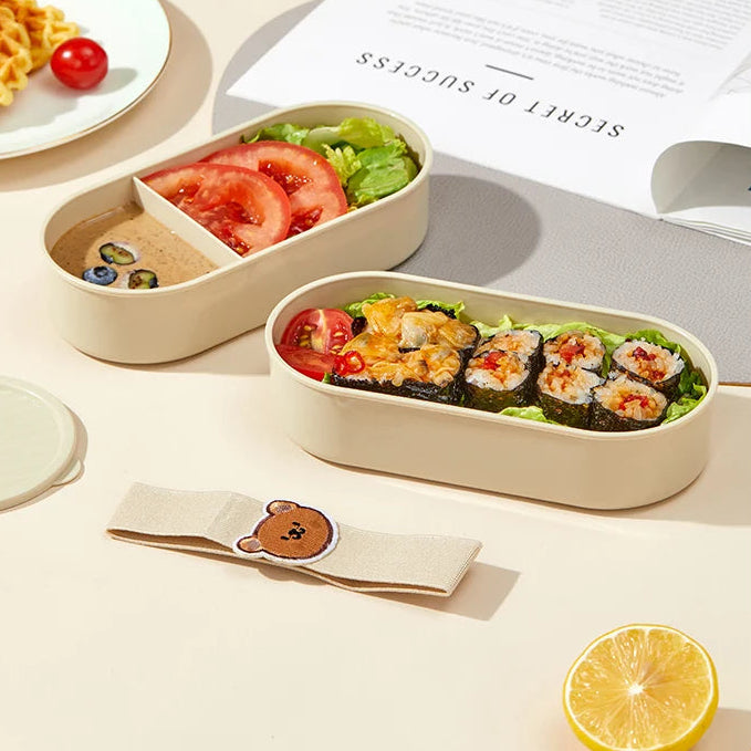 Kawaii bento box with sushi and vegetables on a table with a book in the background