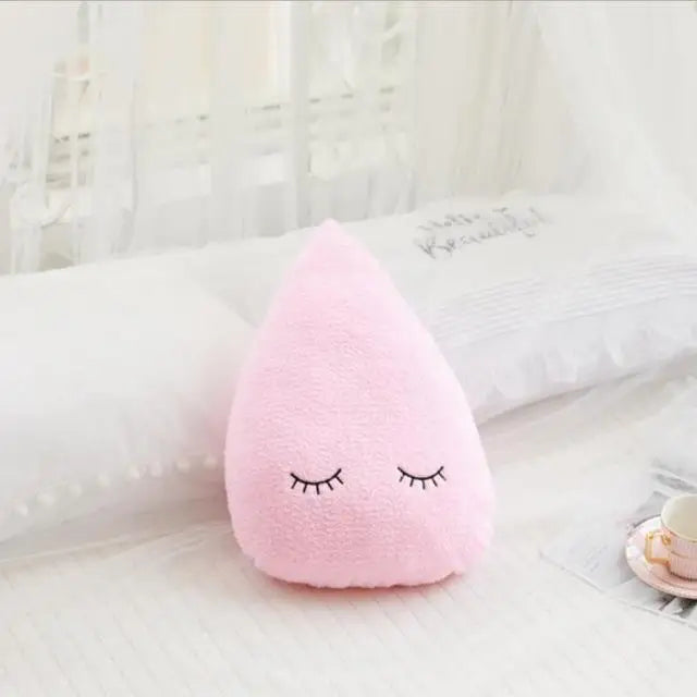 Pink cloud-shaped kawaii pillow with sleep eyes on a white surface