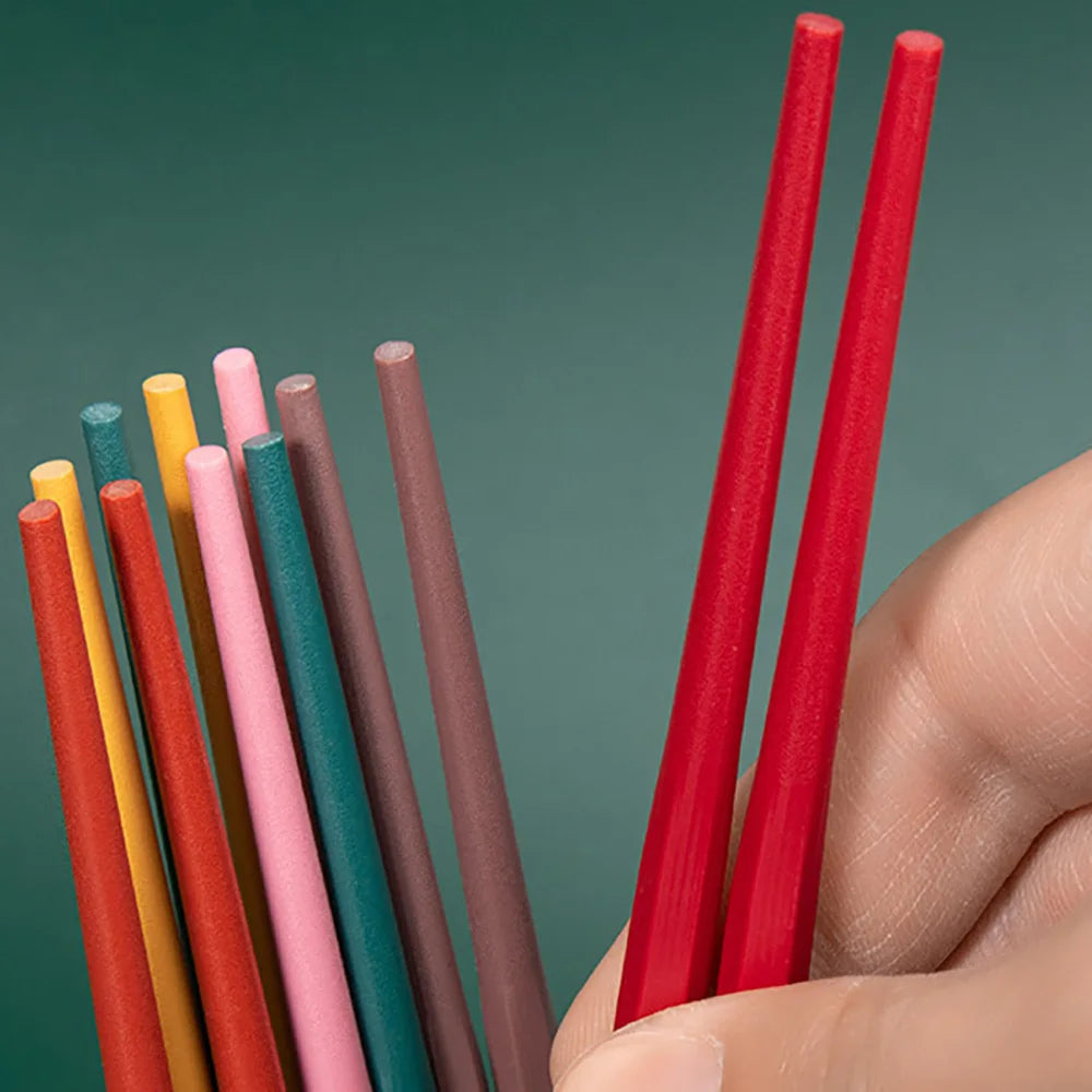 Hand holding red and multicolored kawaii straws against a green background