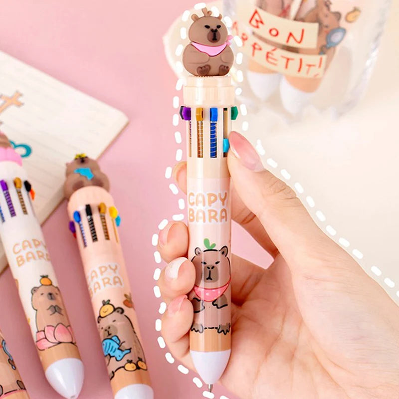 Kawaii capybara-themed stationery set with colorful pens on a pink background