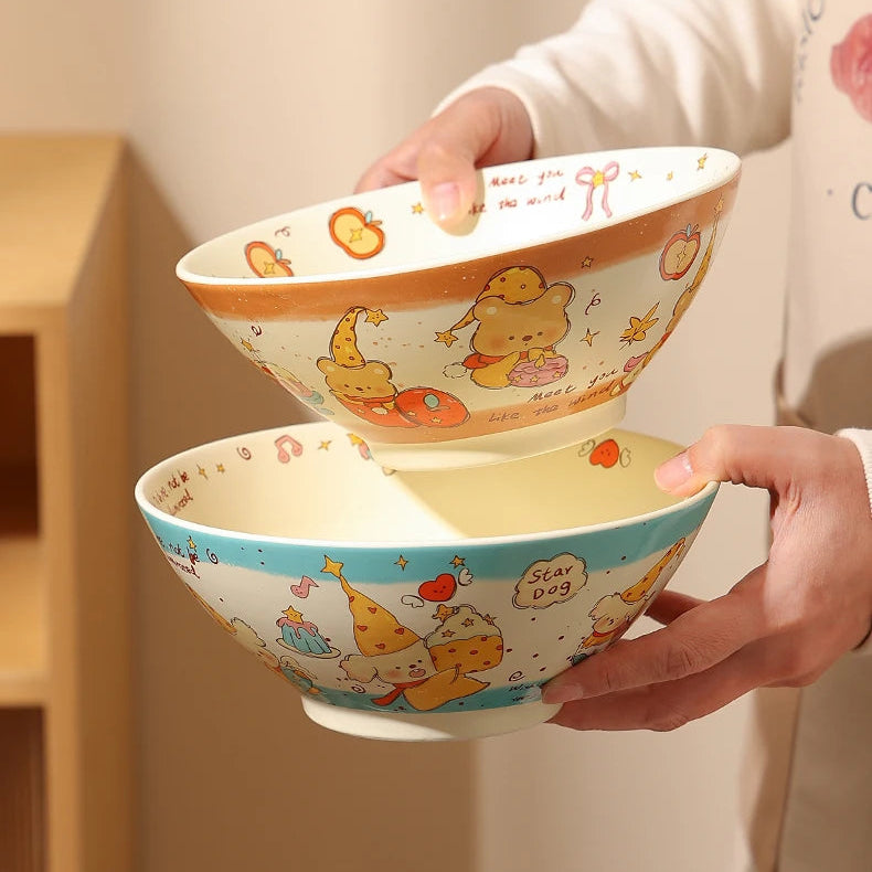 Two stacked ceramic kawaii ramen bowls with cartoon designs held by a person against a neutral background.