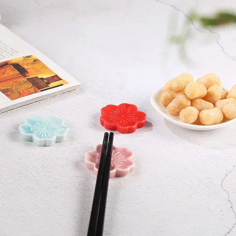 Colorful flower-shaped kawaii chopstick holders on a table with a bowl of food and chopsticks.
