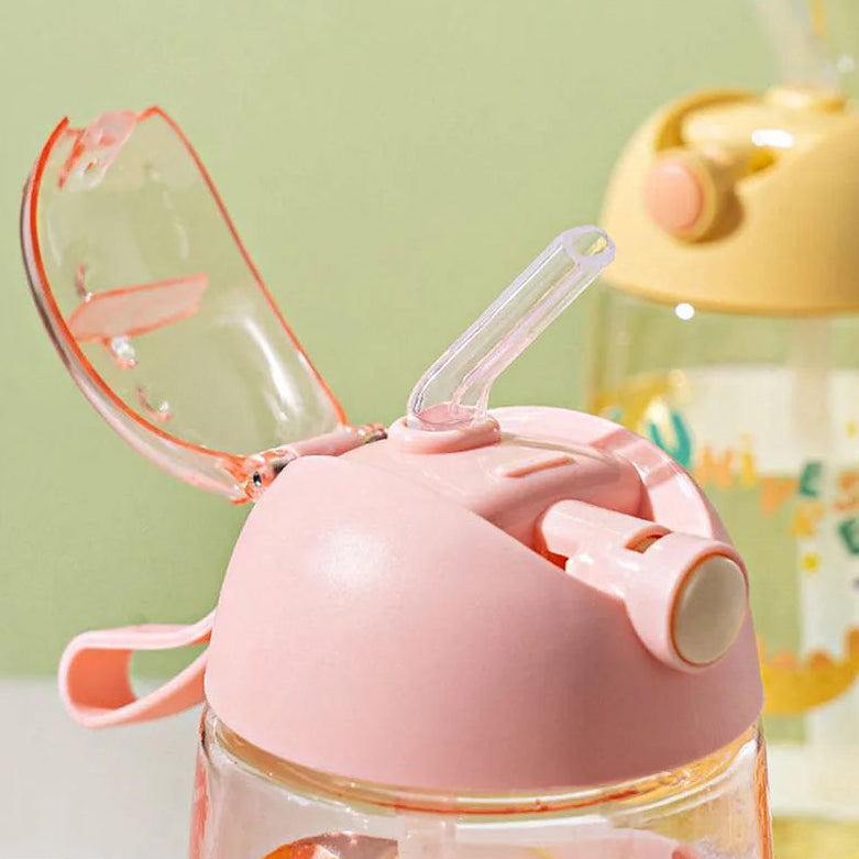 Pink and clear children's kawaii water bottle with straw lid on a light green background