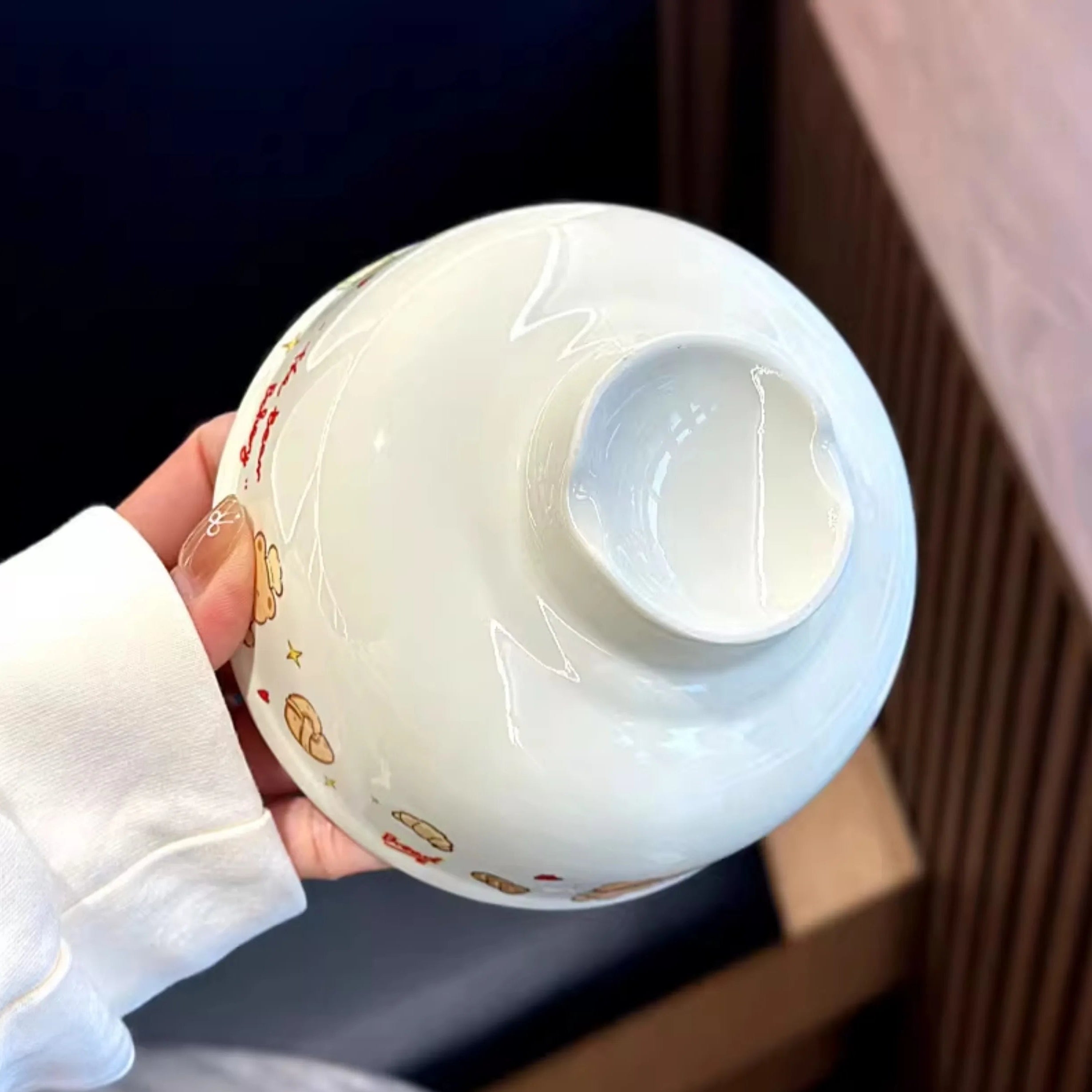 A hand holding a white kawaii ramen bowl
