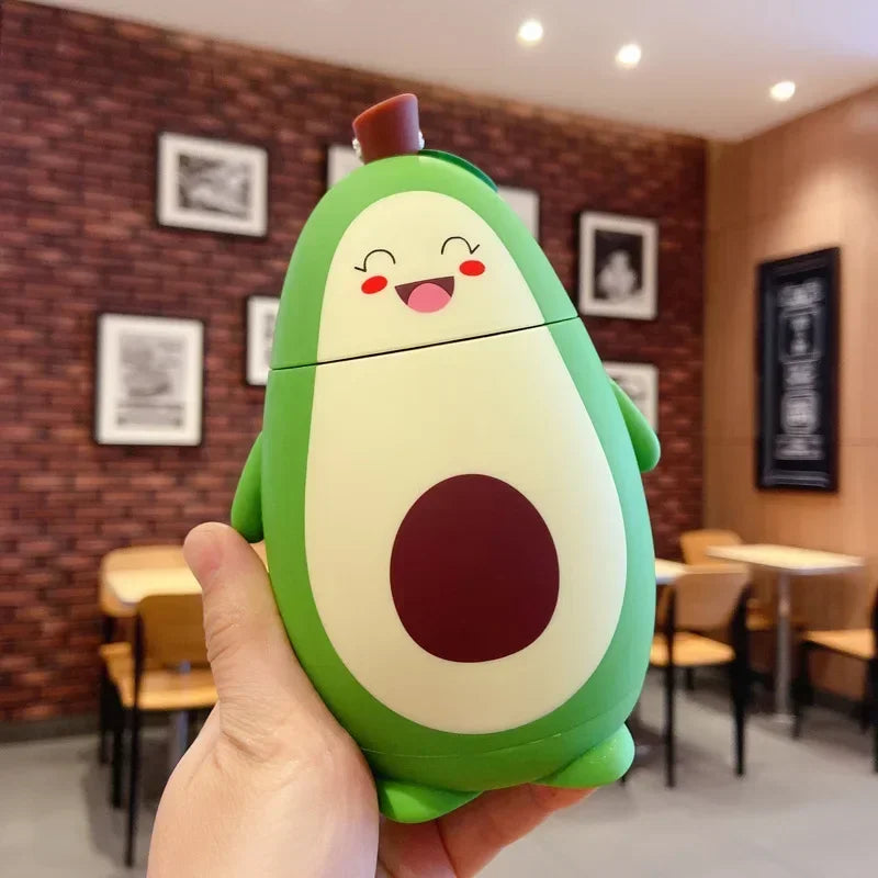 Avocado-shaped kawaii water bottle held in a hand with a blurred restaurant interior background