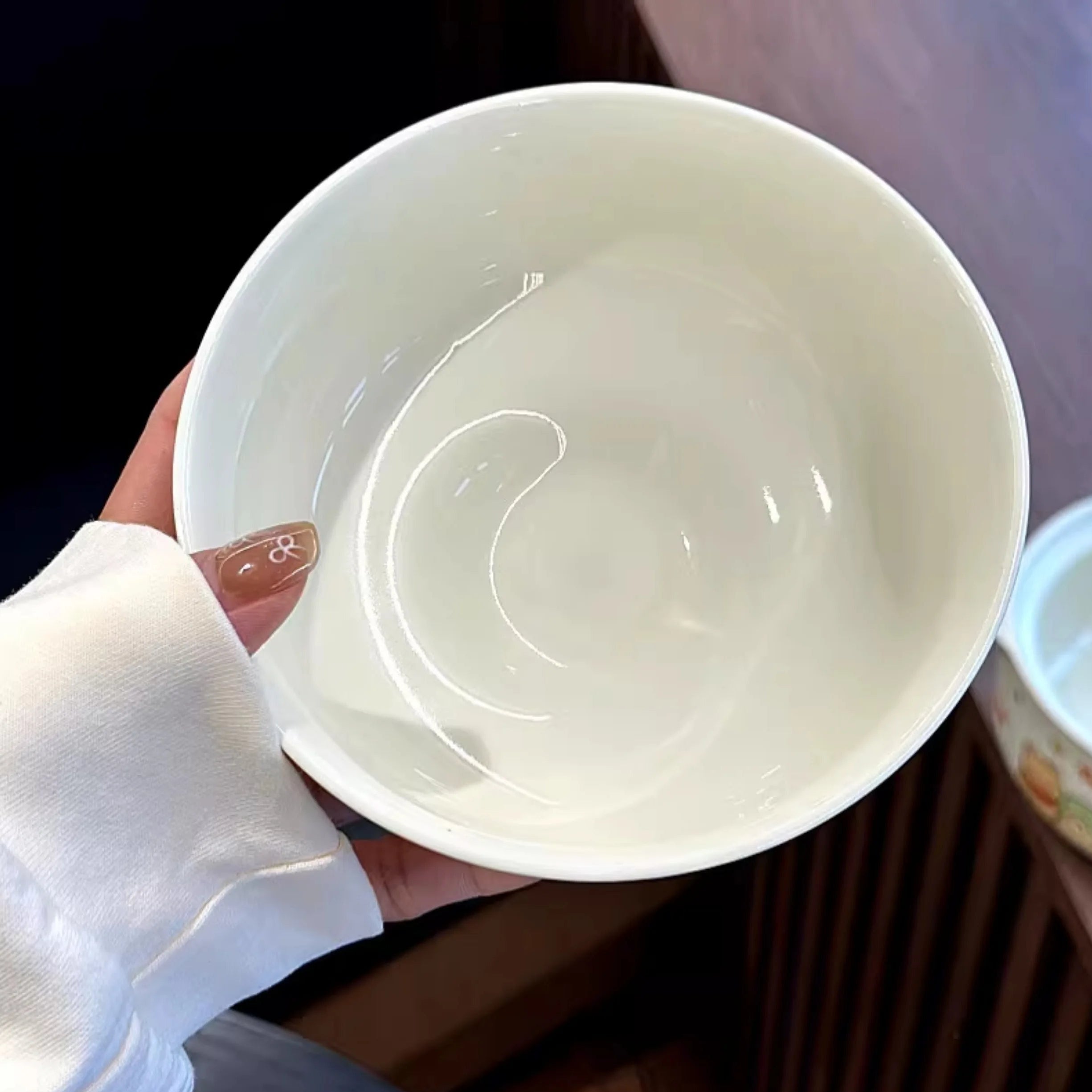 A hand holding a white kawaii ramen bowl