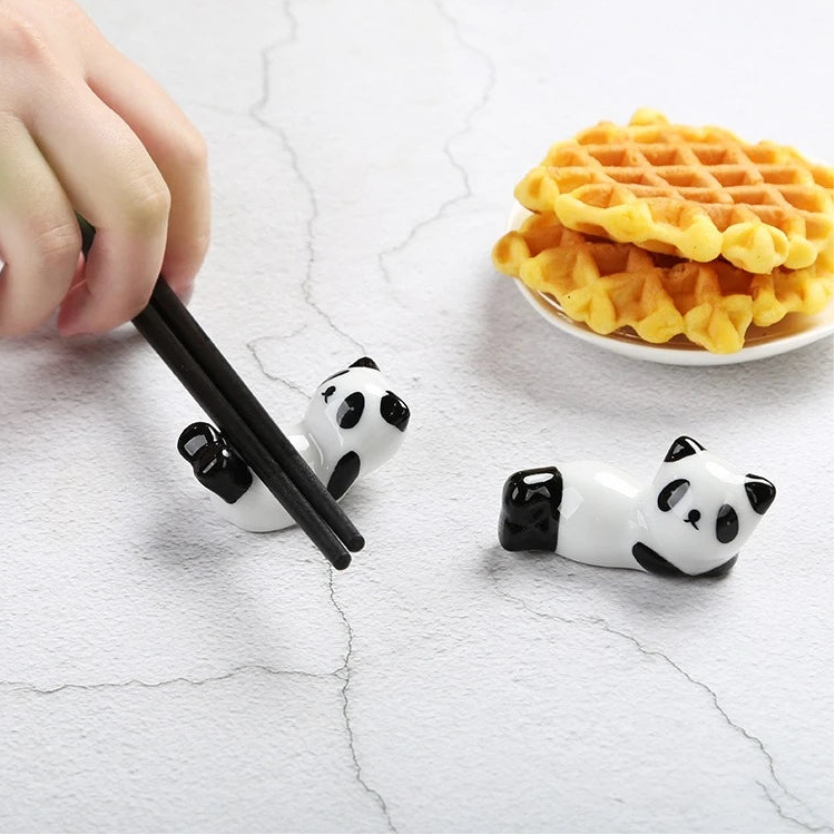 Panda-shaped kawaii chopstick holders with a hand using chopsticks and waffles in the background