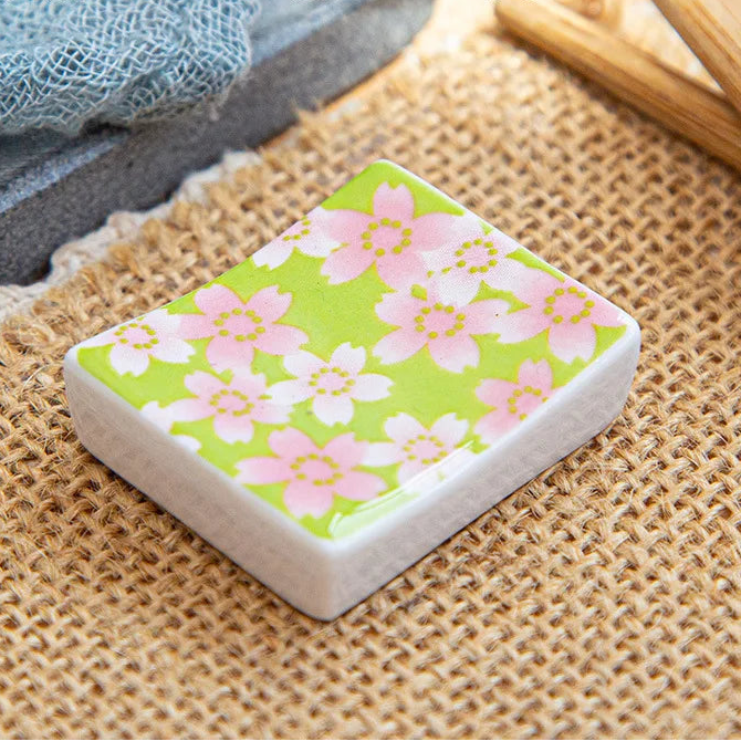 Rectangular kawaii chopstick holders with floral design on a textured surface