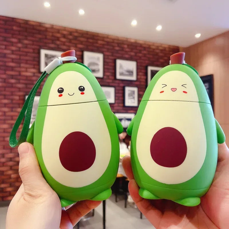 Two avocado-shaped kawaii water bottles held in hands with a blurred indoor background.