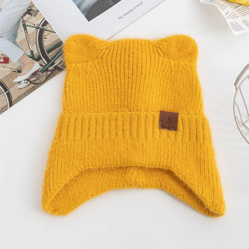 Yellow knitted Kawaii beanie with a brown label on a white surface