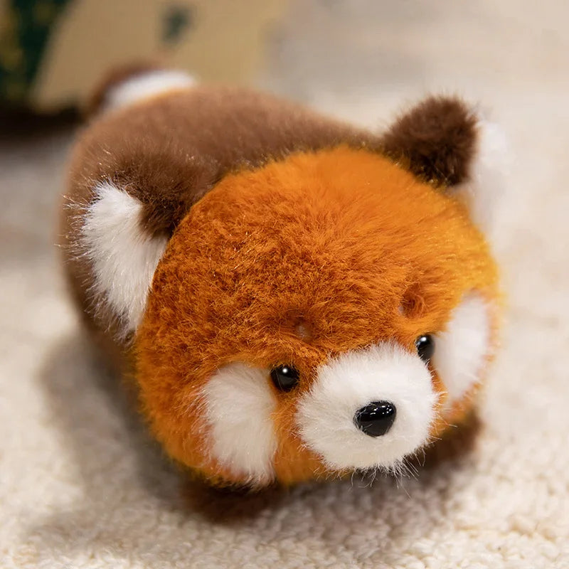 Kawaii plush toy resembling a red panda on a soft surface
