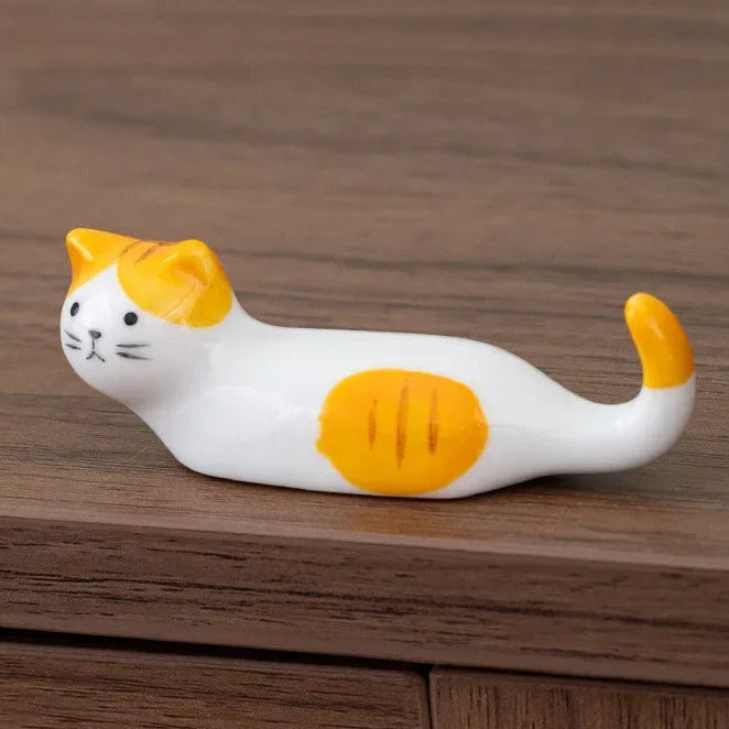 Cat-shaped kawaii chopstick holders with orange and white pattern on a wooden surface