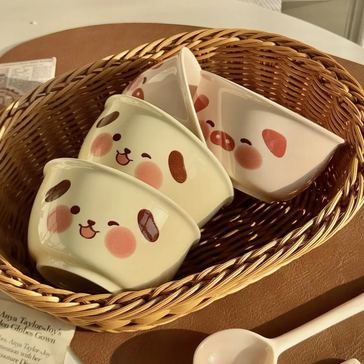 Ceramic kawaii ramen bowls with cartoon face designs in a wicker basket on a wooden surface.