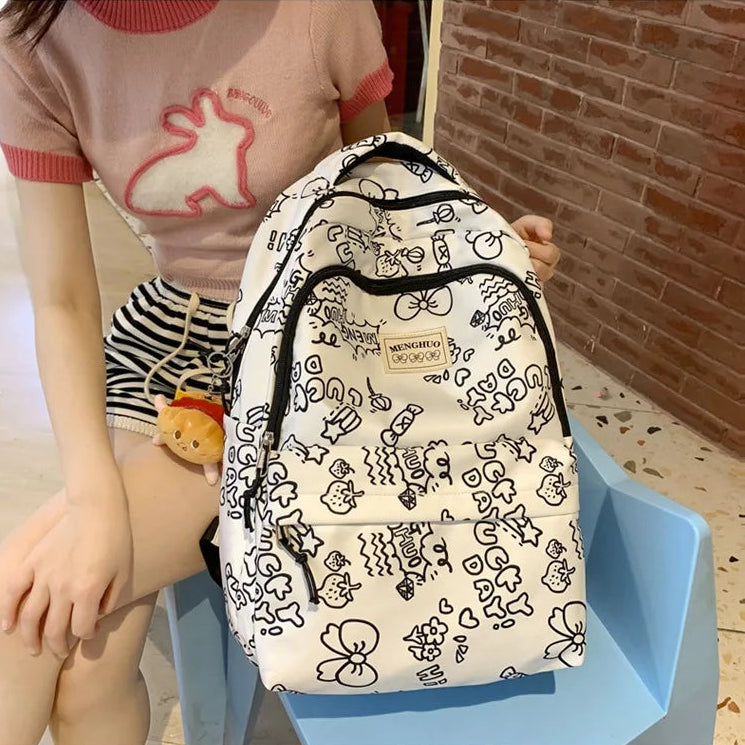 Person holding a white backpack with Kawaii black patterns against a brick wall.