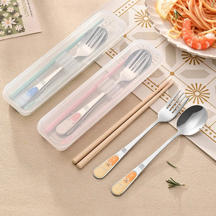 Set of stainless steel kawaii utensils with a clear case on a table with a plate of food.