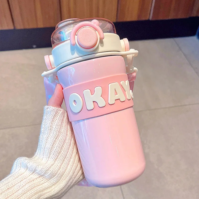 Pink kawaii water bottle with 'OKAY' text held by a person wearing white socks.