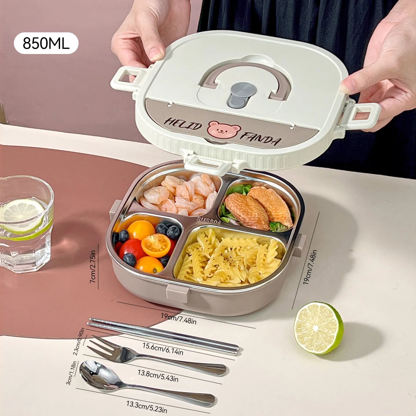 Kawaii meal prep container with compartments of food on a table with utensils and a glass of water.