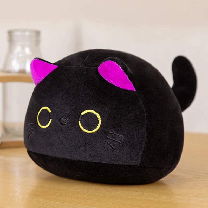 Black kawaii plush cat toy with pink ears on a wooden surface