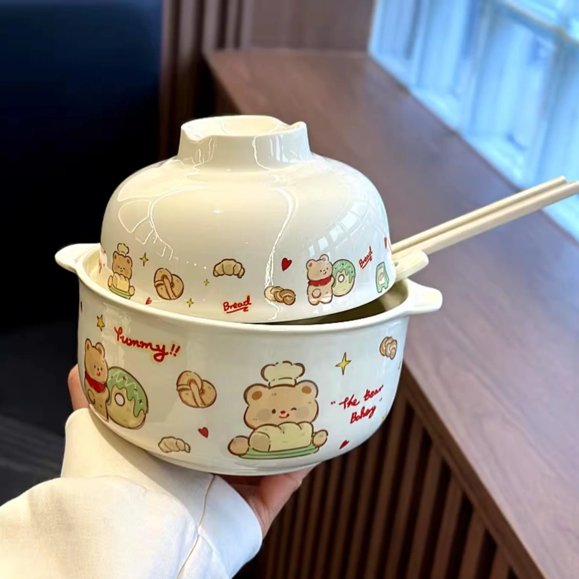 A hand holding a large cartoon bear themed kawaii ramen bowl