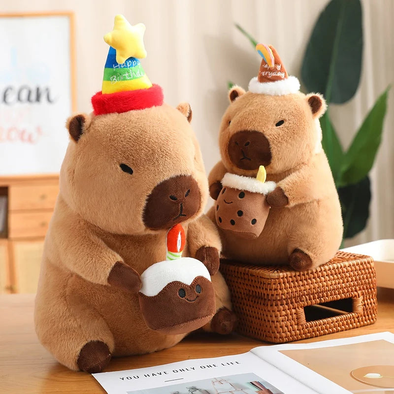 Two brown capybara plush toys with birthday hats on a wooden surface.