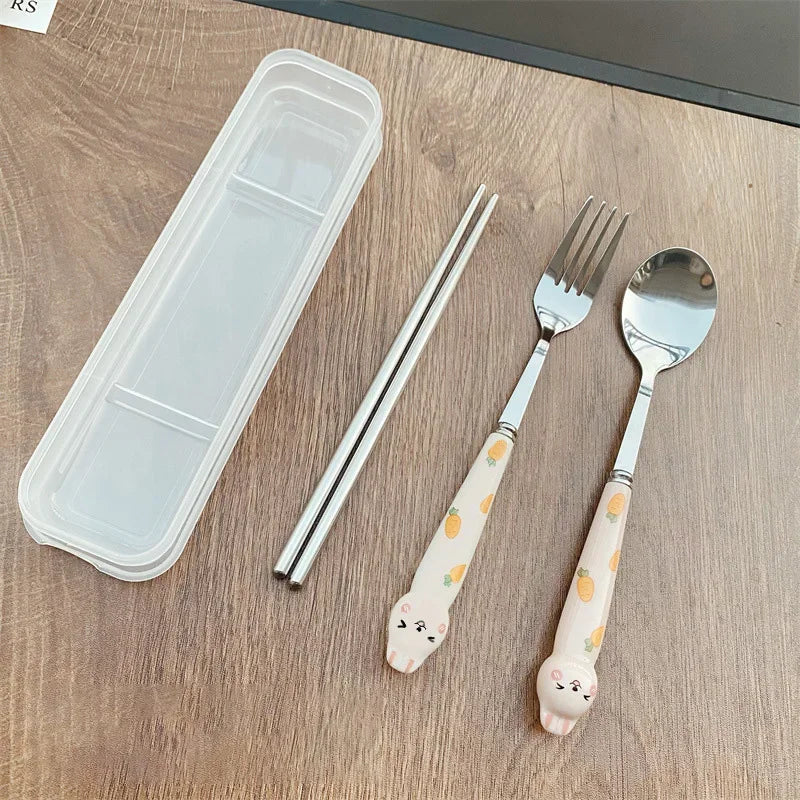 Set of silver kawaii utensils with animal handles on a wooden surface, including a clear plastic case.