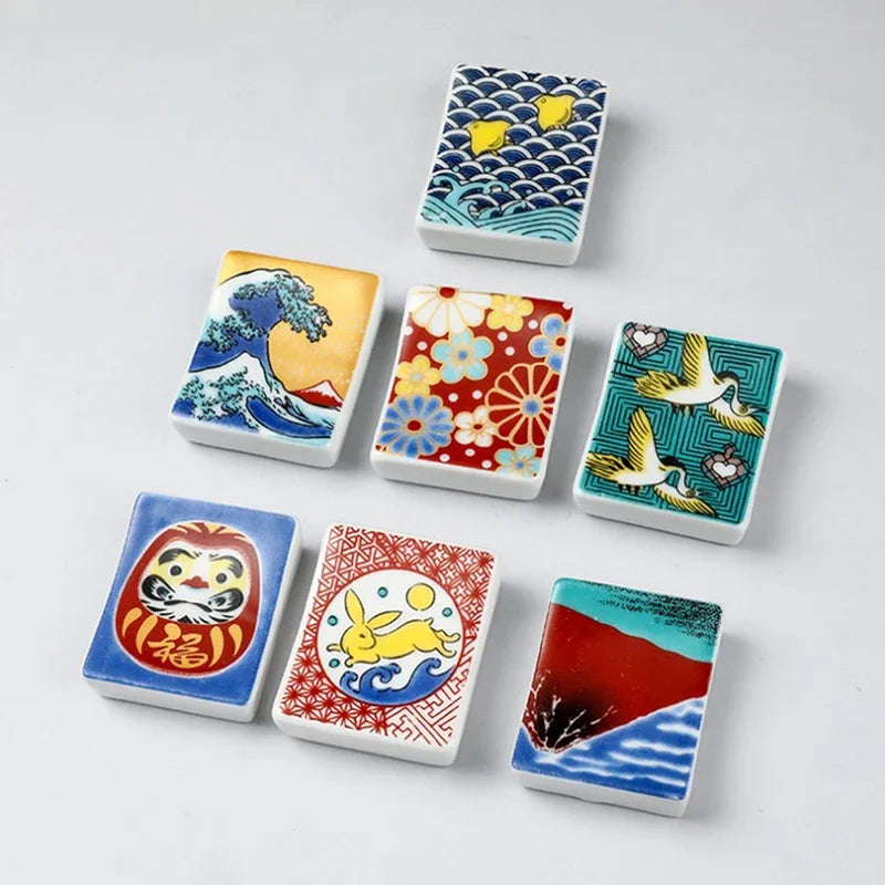 Set of small square kawaii chopstick holders with various designs on a light gray background