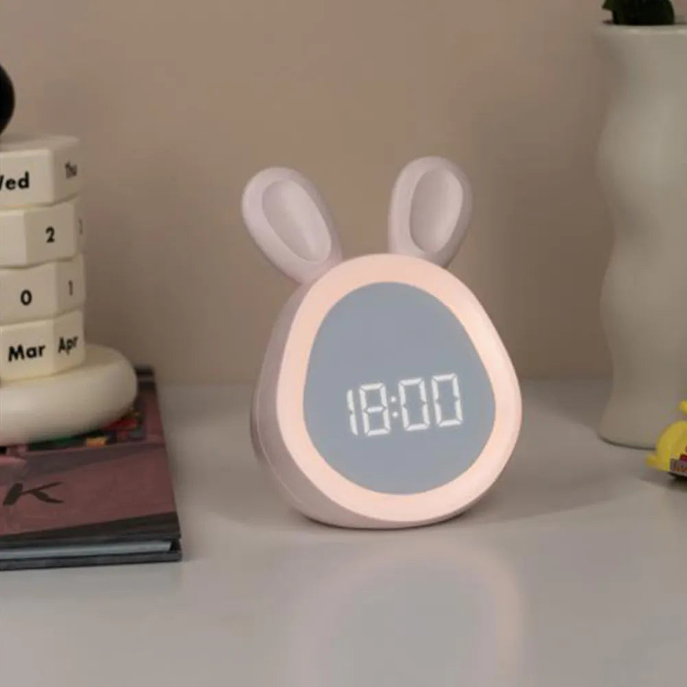 Cute rabbit-shaped kawaii clock on a surface with books and a plant in the background