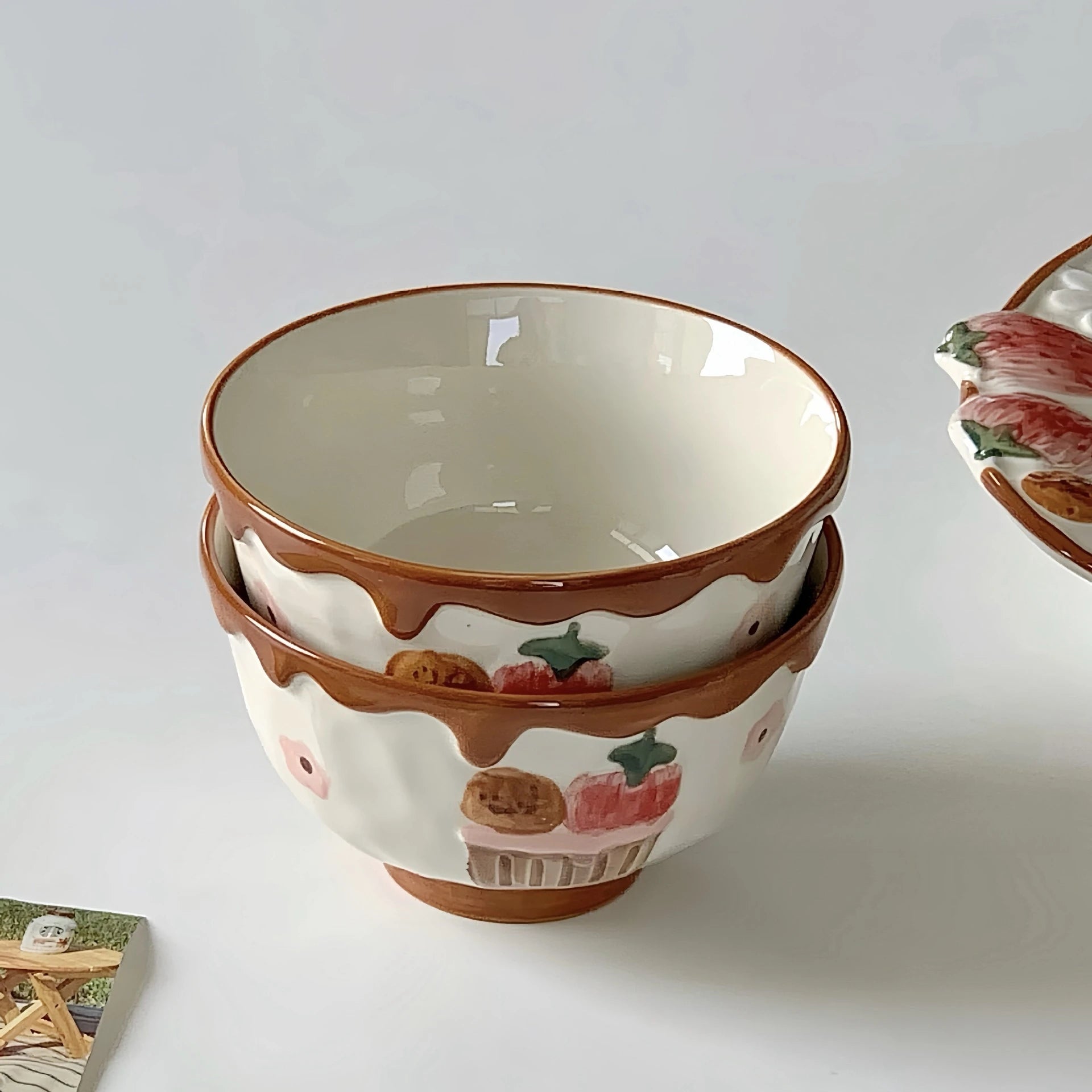 Stack of ceramic kawaii ramen bowls with fruit design on a white background