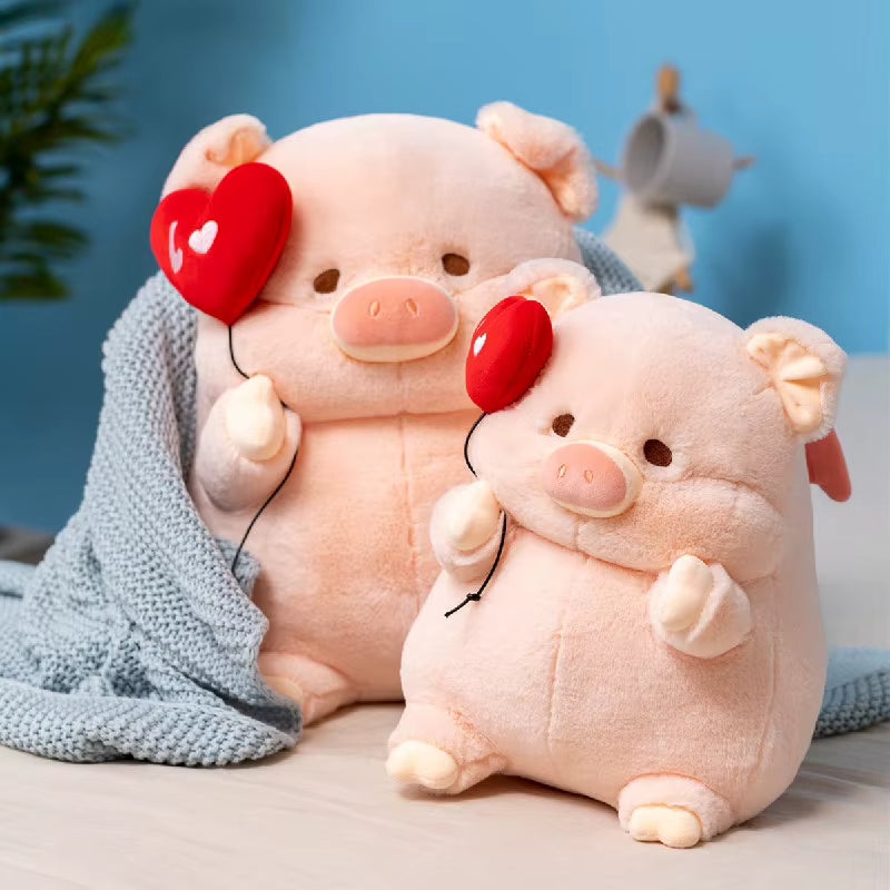 Two cute pink plush pig toys holding red heart-shaped balloons, styled with a light blue knitted blanket against a blue background.