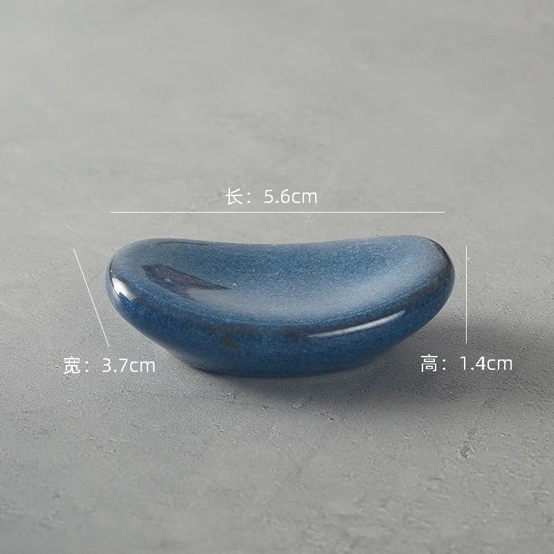 Blue ceramic kawaii chopstick holders on a gray background with measurements indicated