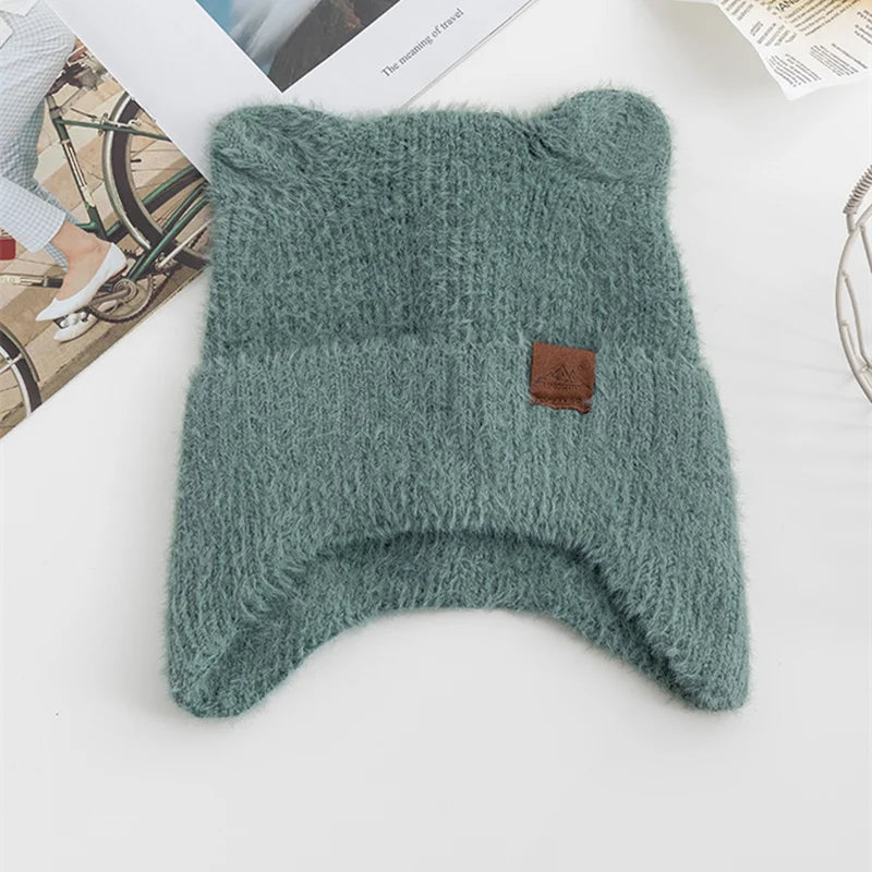 Green knitted Kawaii hat with a brown tag on a white surface