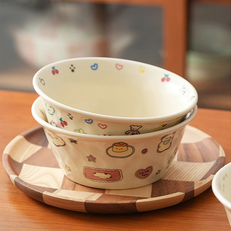 Two ceramic kawaii ramen bowls with cartoon designs on a wooden tray