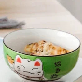 Green ceramic kawaii bowl with a cat design containing food on a wooden surface