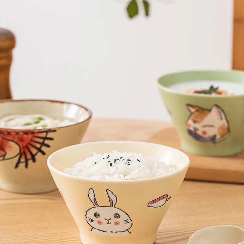Three ceramic kawaii ramen bowls with cute designs on a wooden table