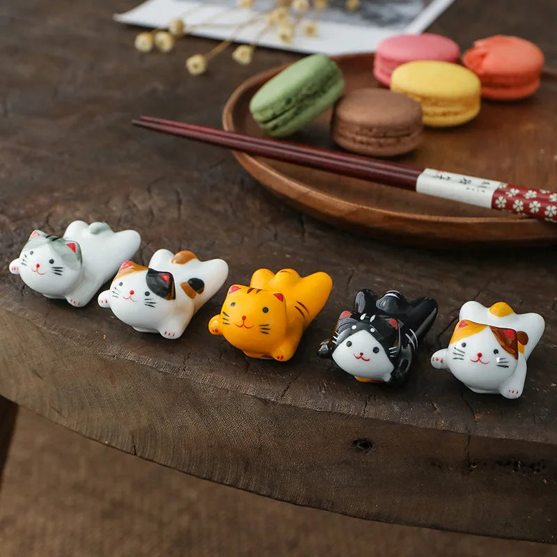 Set of kawaii cat-shaped ceramic hair clips on a wooden surface with macarons in the background.