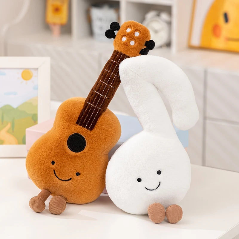 Two kawaii plush toys, one resembling a guitar and the other a cloud, with smiling faces on a white surface.