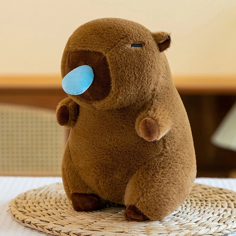 Brown kawaii plush toy resembling a bear with a blue nose on a woven mat.