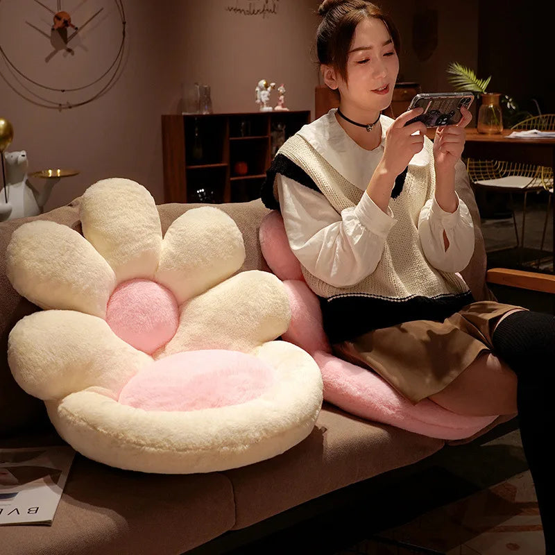 Woman sitting on a couch with a large flower-shaped kawaii cushion, taking a photo with her phone.