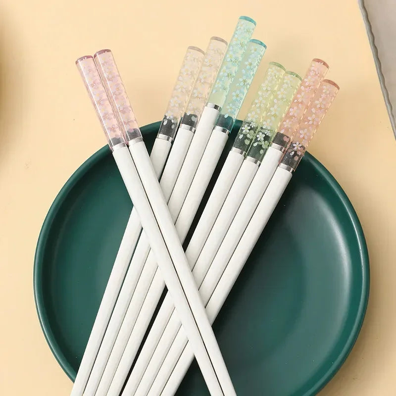 White kawaii chopsticks with colorful glittery tips on a green plate against a beige background