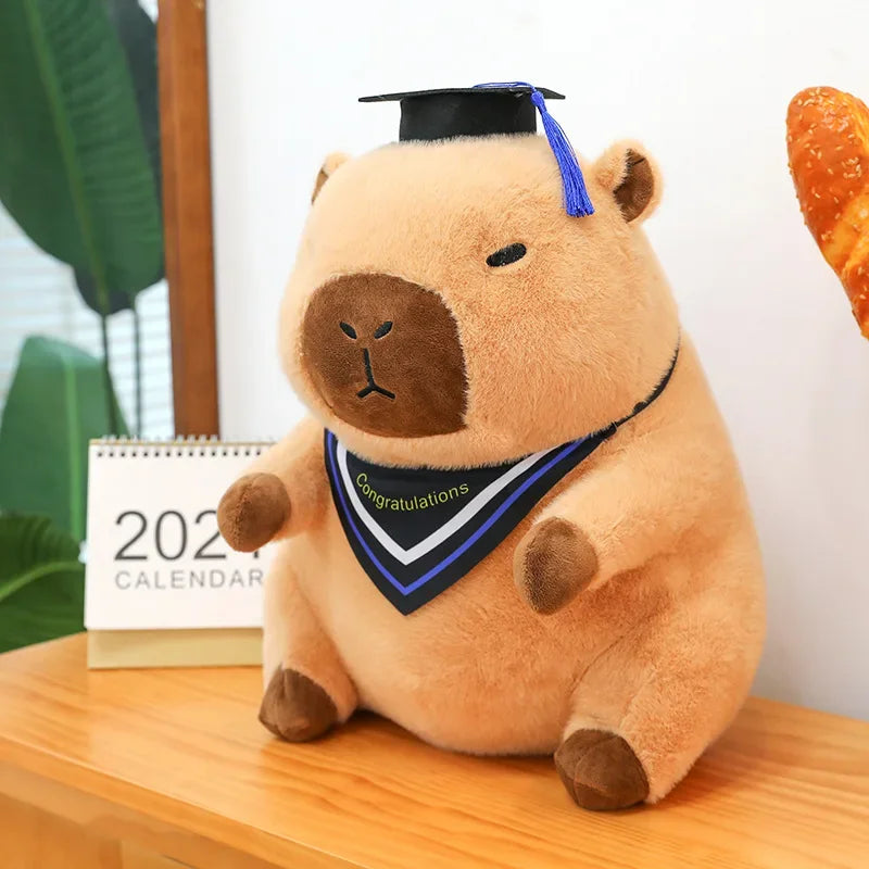 Kawaii plush toy bear wearing a graduation cap and gown on a wooden surface with a 2022 calendar in the background.