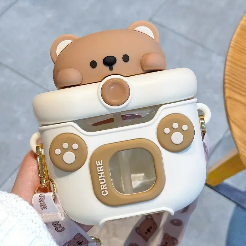 Cute bear-shaped kawaii water bottle with a white lid held by a hand on a light gray background
