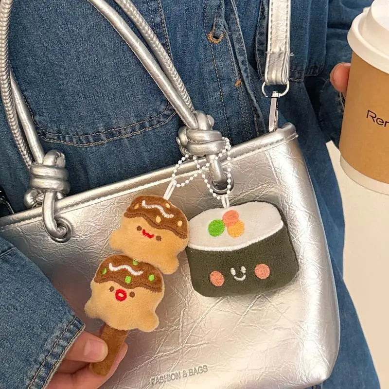 Silver handbag with kawaii ice cream and sushi keychains held by a person wearing a denim jacket.