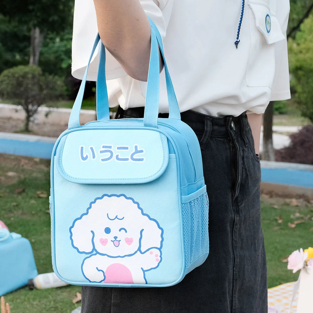 Person holding a blue kawaii lunch bag with a cartoon character design outdoors.