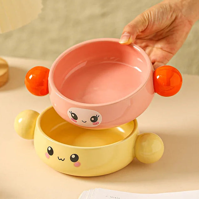Ceramic double-layered kawaii ramen bowl with cartoon design held by a hand on a beige background