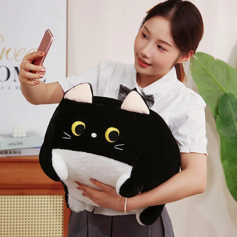 Person holding a black and white cat-shaped kawaii plush toy indoors.
