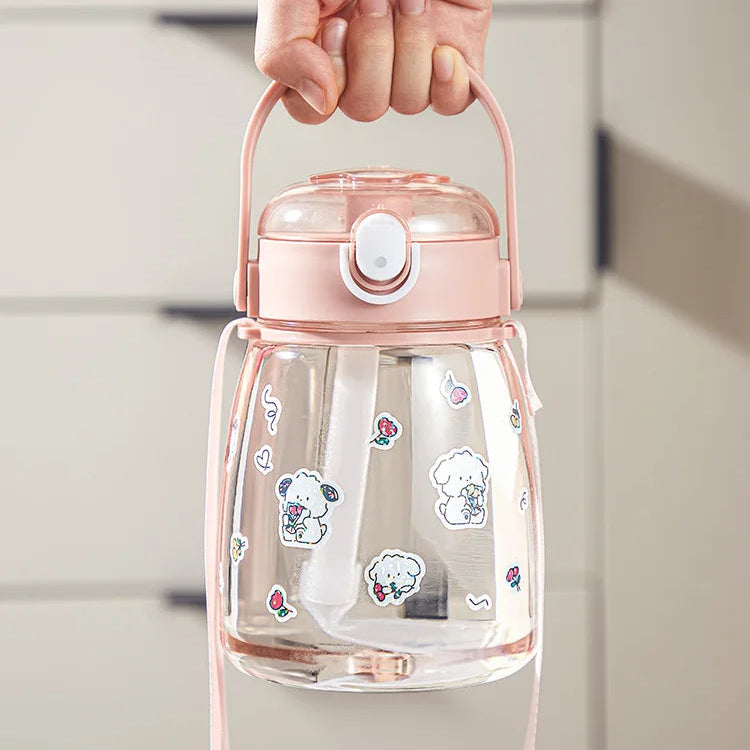 Clear kawaii water bottle with pink lid and handle, featuring cartoon stickers, held by a hand.