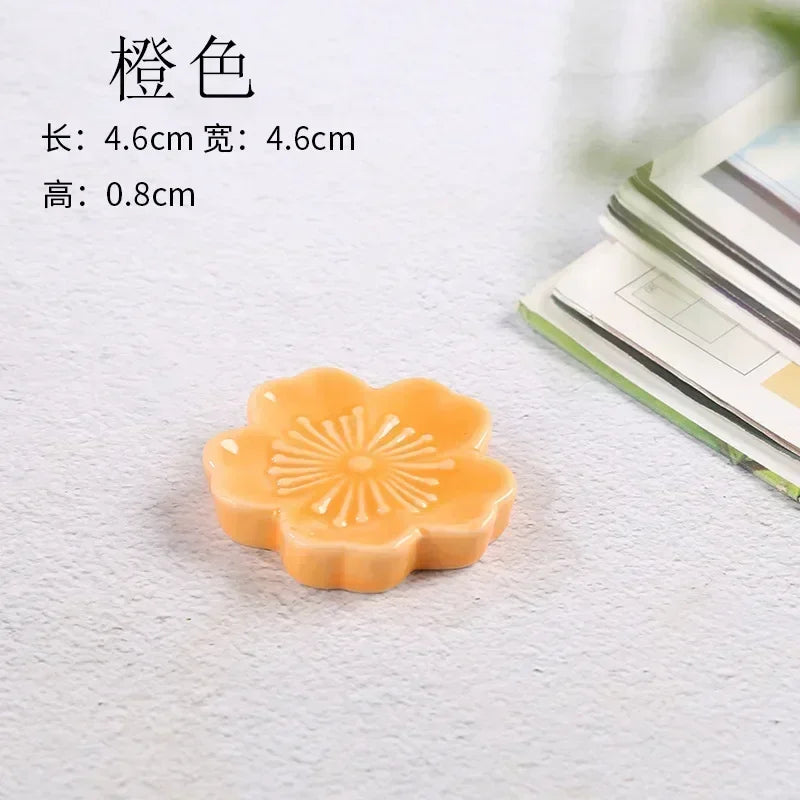Orange flower-shaped kawaii chopstick holder on a light gray surface with text indicating dimensions.