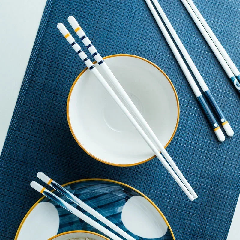 White kawaii chopsticks with blue accents on a ceramic plate and blue placemat