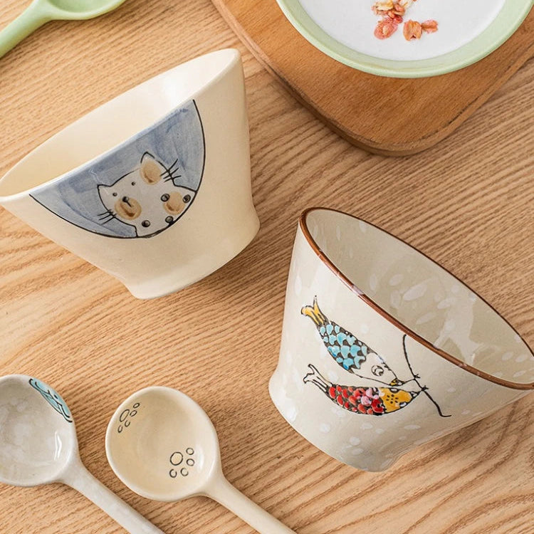 Ceramic kawaii ramen bowls and spoons with cat designs on a wooden surface