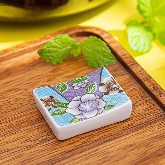 Square ceramic kawaii chopstick holders with floral design on a wooden surface